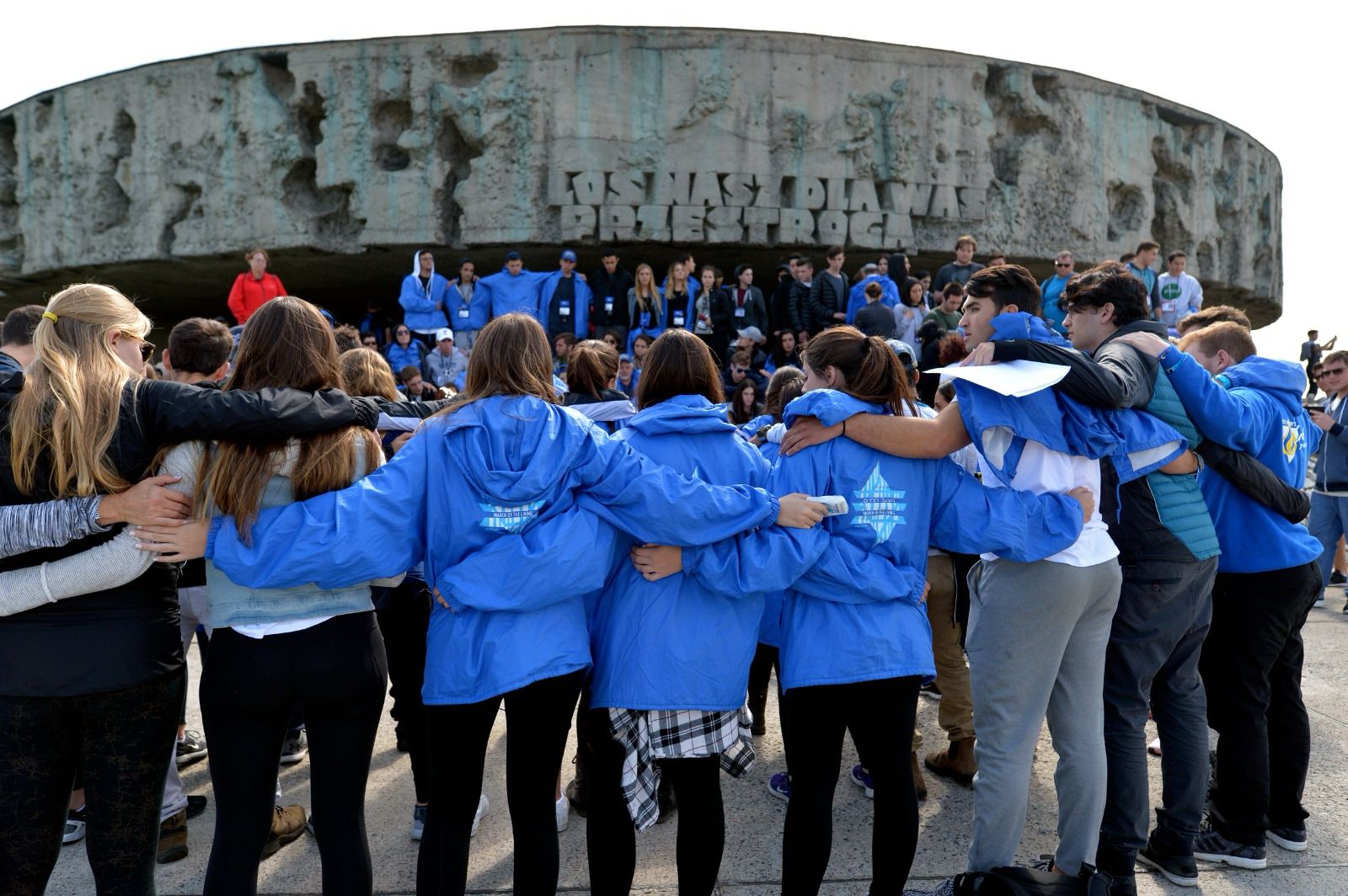 March of the Living students in blue jackets at a memorial ceremony at Majdanek