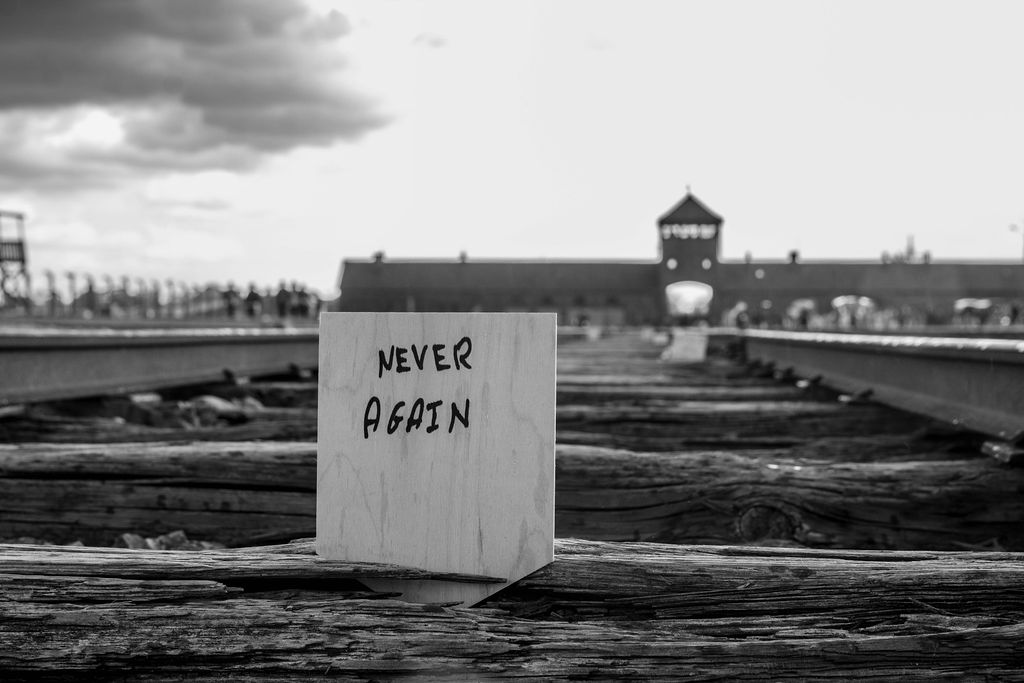 A handwritten Never Again plaque on the railway tracks at Birkenau