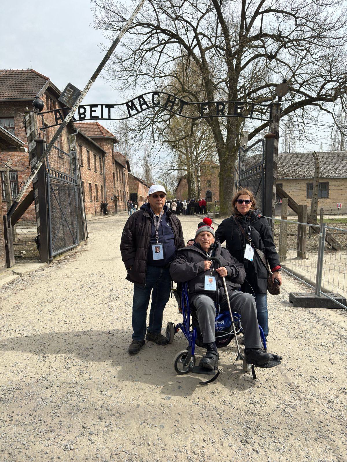 Harry Rozendaal with his daughter Dr. Betty Rozendaal and son-in-law Sonny Goldstein under the Arbeit Macht Frei sign