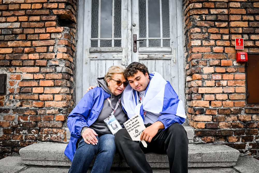 A Holocaust survivor and a young marcher sitting together at Auschwitz