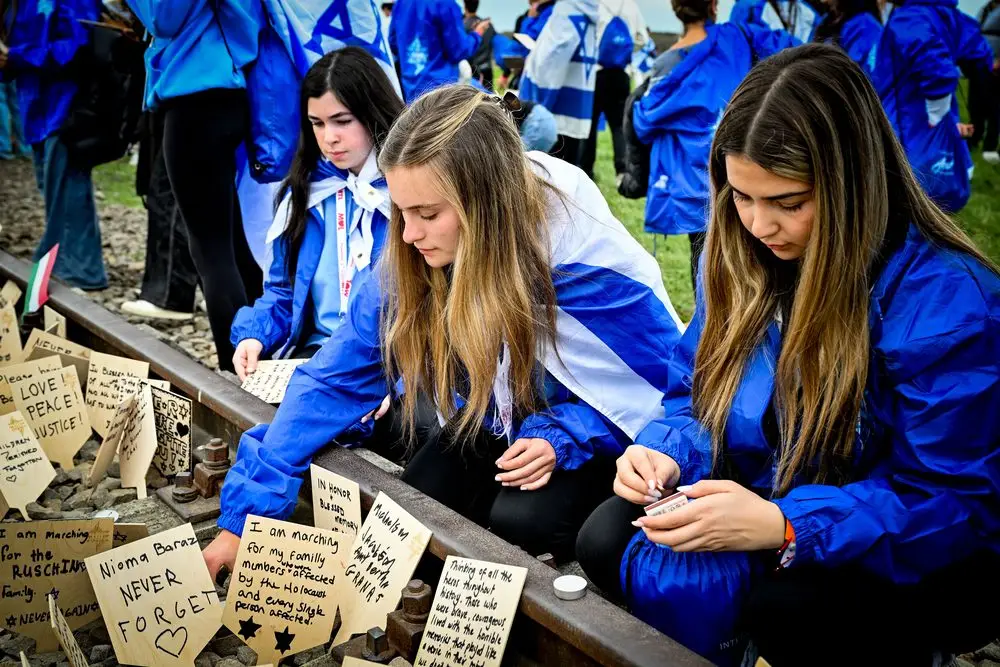 Young Canadian marchers placing handwritten memorials on the tracks at Birkenau