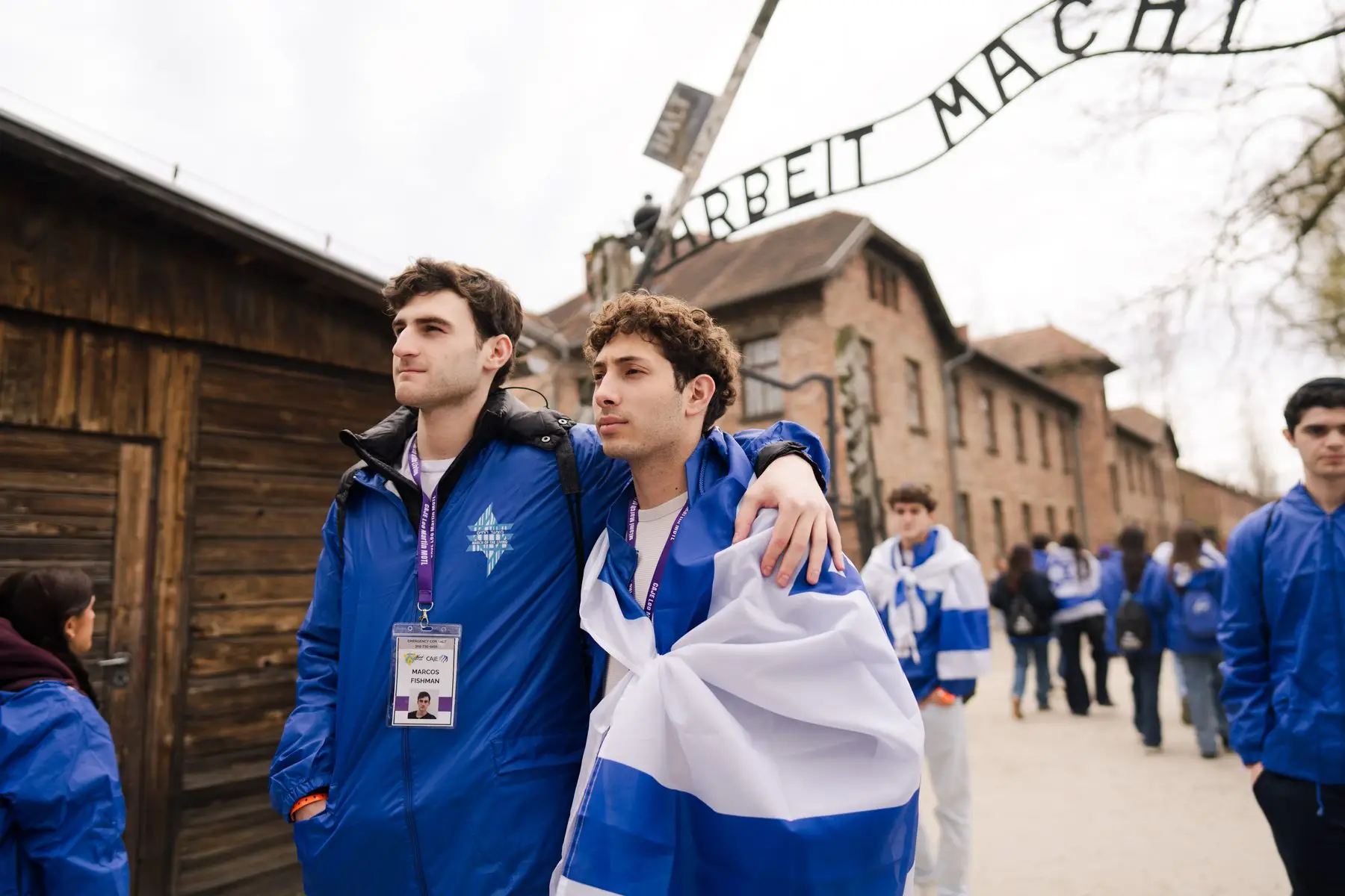 Two young marchers wrapped in an Israeli flag beneath the Auschwitz gate