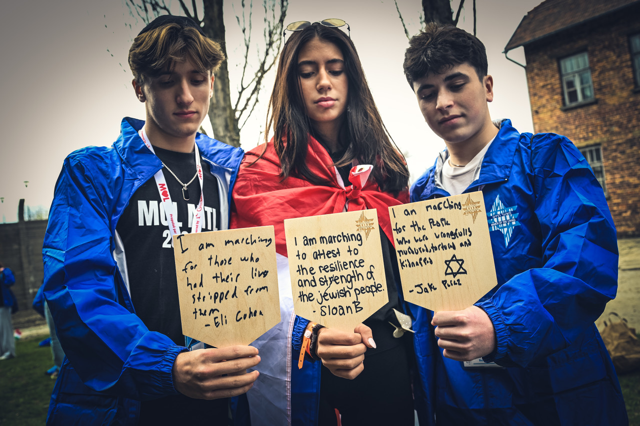 Participants holding handwritten memorial plaques