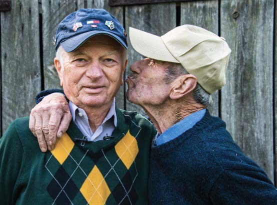 Zygmunt Krynski kissing Sidney Zoltak on the cheek in front of the barn where his family hid Sidney during the war