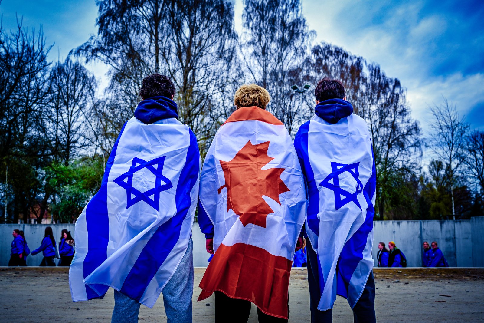 Three students wrapped in Israeli and Canadian flags at Auschwitz-Birkenau