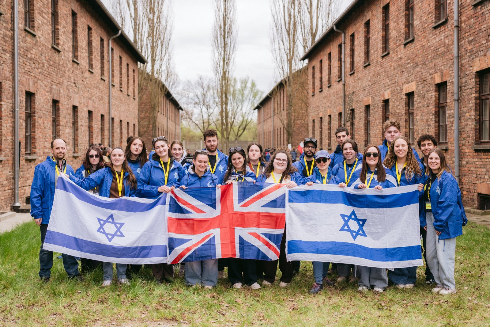 The UK Delegation holding Israeli and British flags at Auschwitz